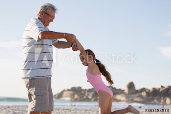 Grandfather and granddaughter playing on sunny beach