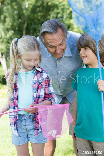 Grandfather and grandkids catching butterflies in nets