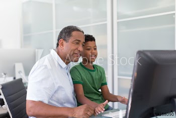 Grandfather helping grandson with homework at computer