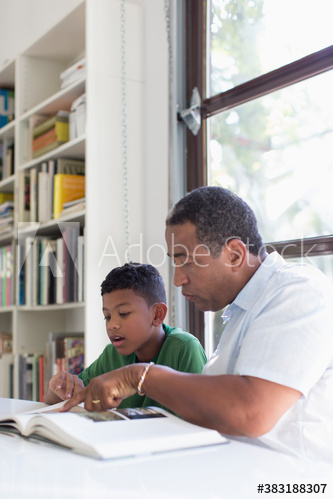 Grandfather helping grandson with homework at table