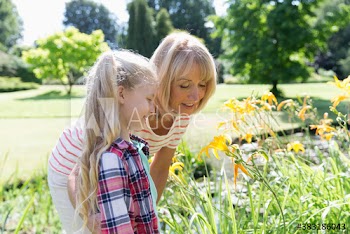 Grandmother and granddaughter looking at flowers in sunny garden