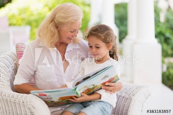 Grandmother and granddaughter reading book on patio