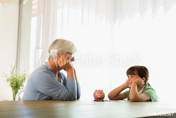 Grandmother and granddaughter with piggybank at table