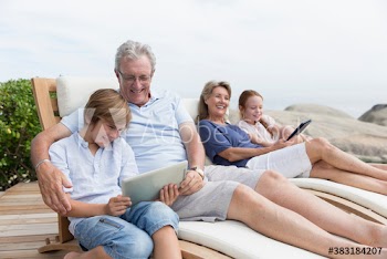 Grandparents and grandkids using digital tablets on lounge chairs