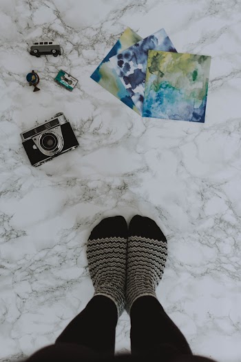 Gray and Black Camera Near Person's Feet Wearing Striped Socks