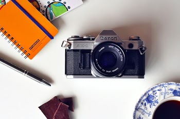 Gray and Black Canon Mirrorless Camera Beside Blue and White Ceramic Plate