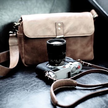 gray and black DSLR camera beside brown leather sling bag