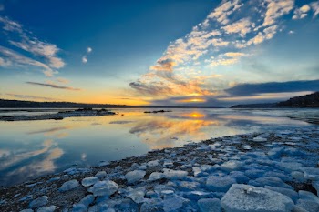 Gray and Black Rocks Near Body of Water Under Blue and White Cloudy Sky