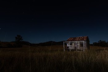 gray and brown wooden house surrounded by grass near mountain