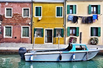 gray and teal boat on dock beside red, yellow, and white painted houses
