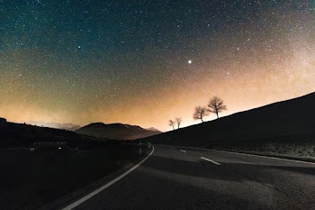 gray asphalt road near silhouette of mountain at night time