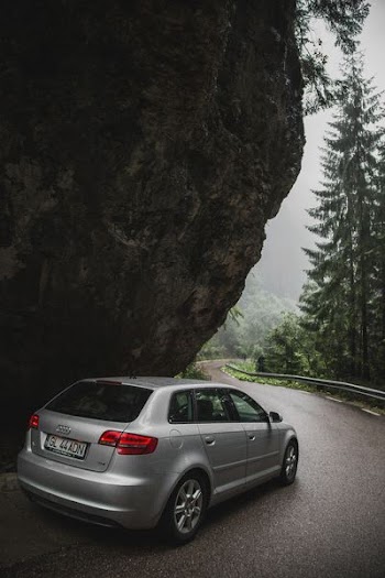 gray Audi 5-door hatchback passing on black rock formation
