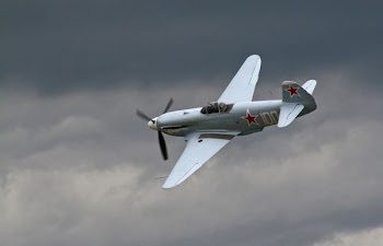 gray bi-plane under gray clouds