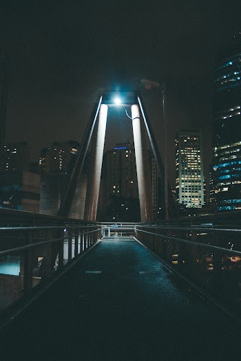 Gray Bridge Near City Buildings With Lights Turned Near at Night