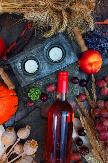 Gray Candle Holder Near Glass Bottle and Round Red Fruit on Gray Wooden Surface