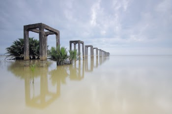 Gray Concrete Arches on Body of Water Under White Skies