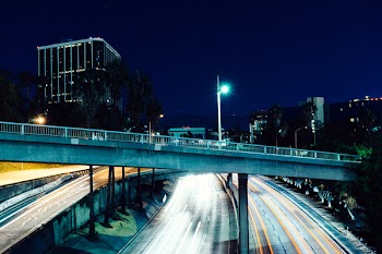 Gray Concrete Bridge Beside High Rise Building at Night
