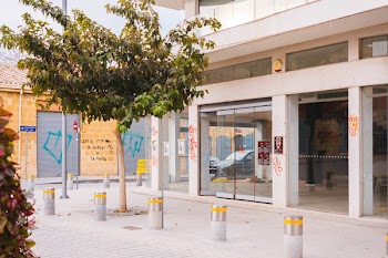 Gray Concrete Building Near Green-leafed Tree and Concrete Posts