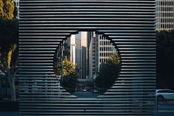 gray concrete building with hole near green trees during daytime