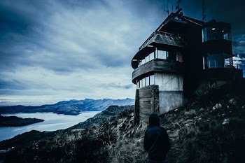 gray concrete house on the rock near body of water photography