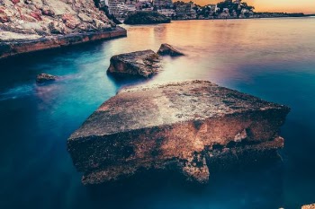 gray concrete slab near coastline under brown sky during daytime