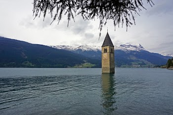 Gray Concrete Tower on Body of Water Under White Skies