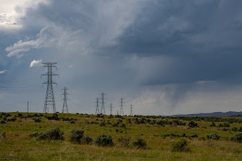 Gray Electric Post on Green Field Under White Clouds and Blue Sky