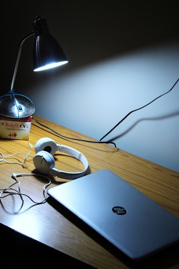 Gray Hp Laptop and White Corded Headphones on Brown Wooden Table
