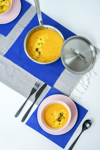 Gray Metal Cooking Pot With Cook Food Beside Bowl and Cutlery Set on Top of Table