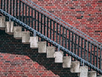 gray metal stair beside red brick wall