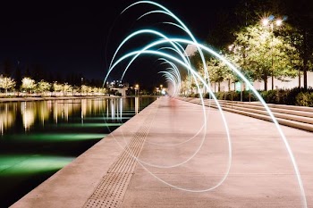 gray pavement beside body of water at night time