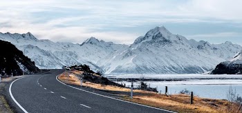 gray road beside body of water fronting mountain