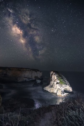 gray rock on body of water under stars