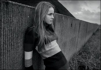 Gray scale photo of a woman leaning on a wall 