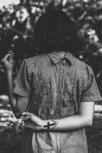gray scale photo of a woman standing in front of bushes