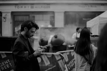 Gray scale photo of man holding smartphone