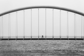gray scale photo of person driving bike on bridge