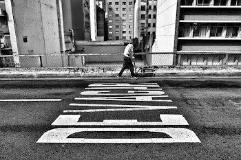 gray scale photography of person walking beside pave road