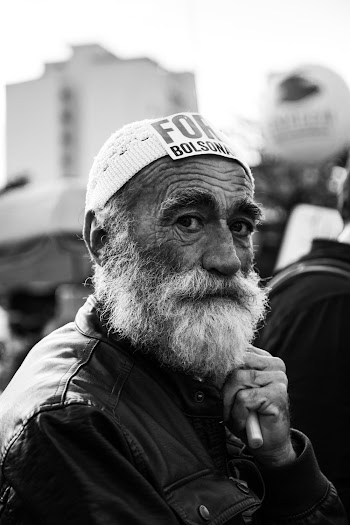 Gray scale portrait photo of an elderly man wearing topi hat