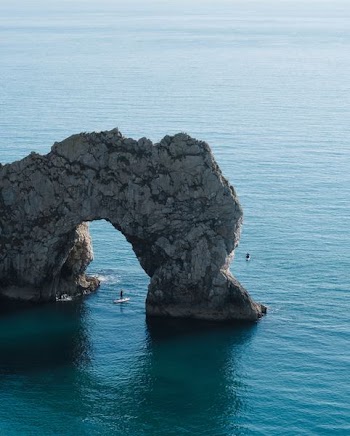 gray stone arch on body of water