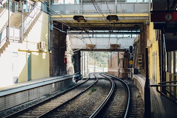 Gray Train Rail Under Yellow and Gray Building