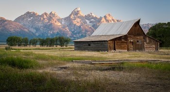 gray wooden barn near the mountain range under the gray skies