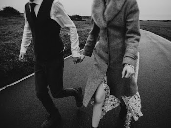Grayscale Close-up Photo of Couple Holding Hands While Walking Down an Empty Road