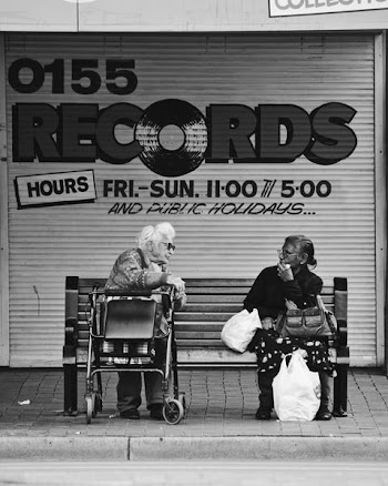 grayscale man and woman sitting on bench