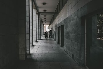 grayscale of person waking in the middle of wall
