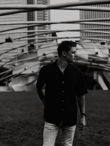 Grayscale Photo Man in Black Shirt Standing Outside Building