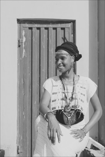 Grayscale Photo Of A  Smiling Woman Wearing A Headdress And Accessories