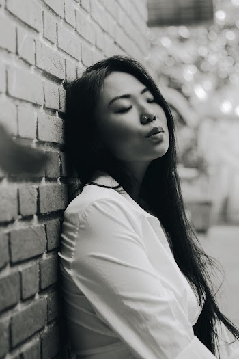 Grayscale Photo of a Woman Leaning on a Wall