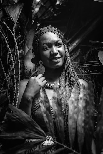 Grayscale photo of a woman posing in front of trees