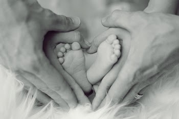 Grayscale Photo of Baby Feet With Father and Mother Hands in Heart Signs